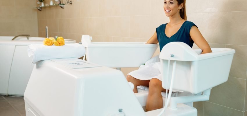 Happy woman enjoying in relaxing arms and leg hydrotherapy at spa center.